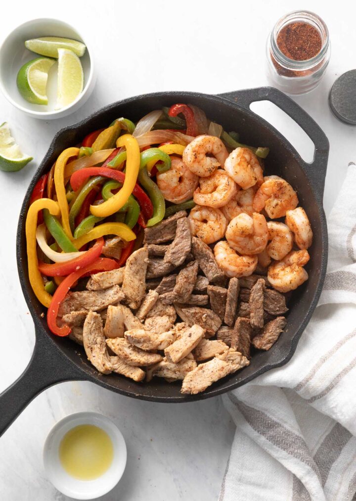 Chicken Steak and Shrimp Fajitas  with sautéed veggies in a black cast iron skillet