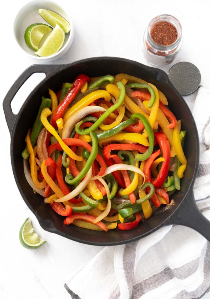 Sautéed Veggies with green, yellow, and red peppers. With white onion in a black cast iron skillet.