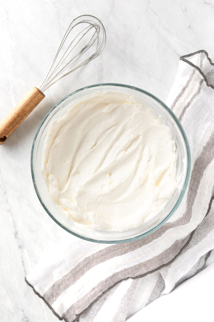 Whipped cream in a bowl with a whisk