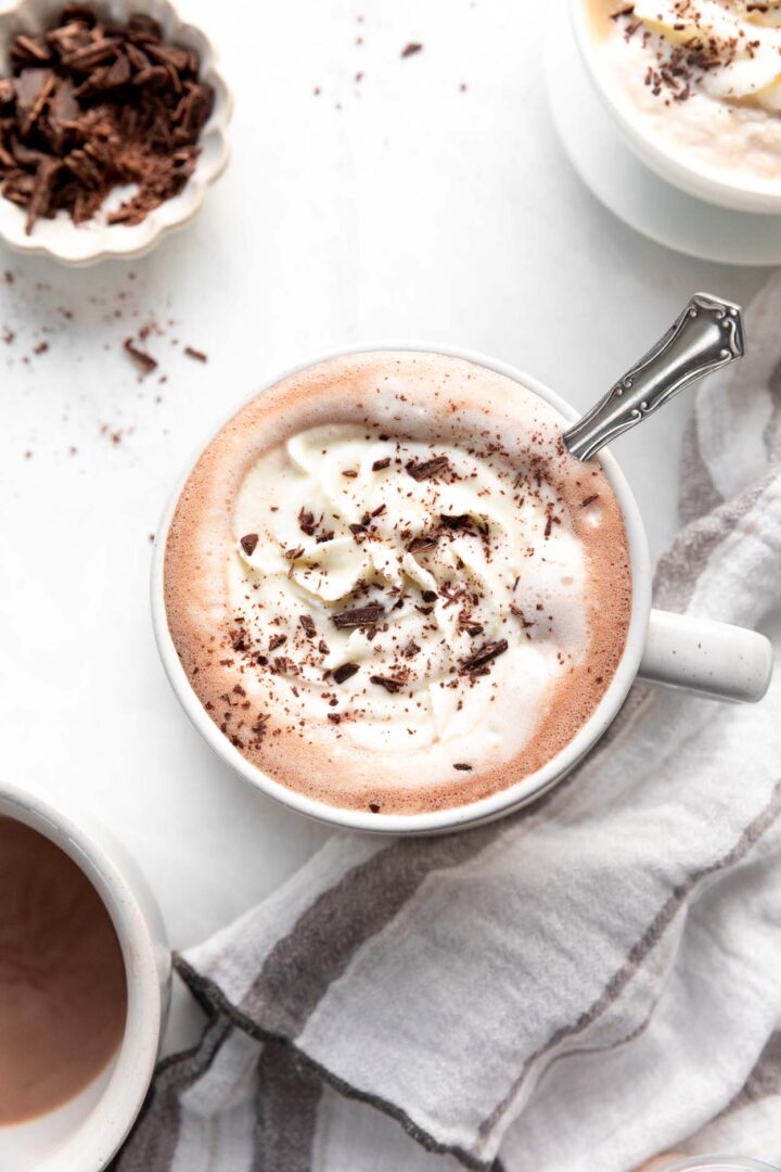 Whipped cream topped on a cup of coffee with shaved chocolate. 
