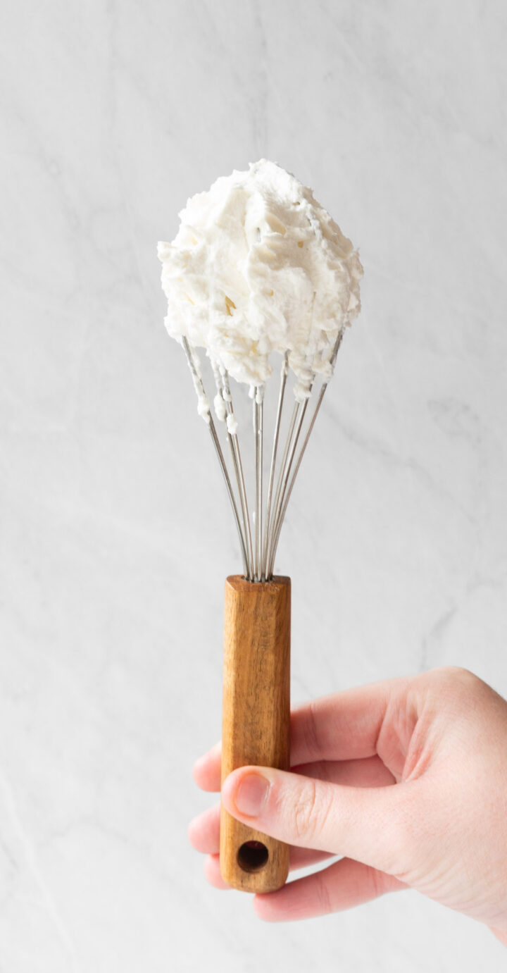 Homemade whipped cream on a whisk.