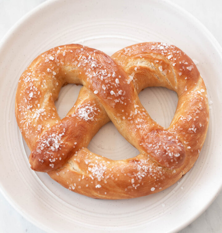 Homemade soft pretzels with coarse salt on a white plate.