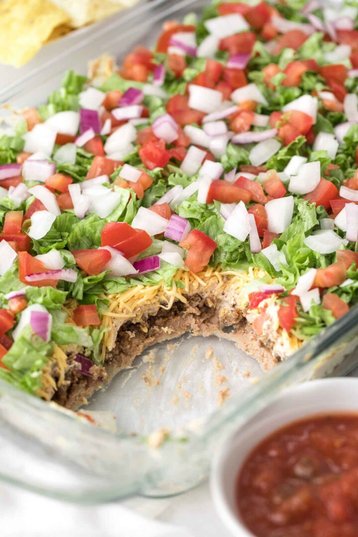 7 Layer Dip in a glass baking dish with tortilla chips
