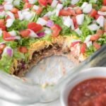 7 Layer dip in a 9x13 glass baking dish with red salsa.