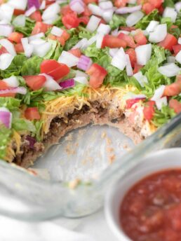 7 Layer dip in a 9x13 glass baking dish with red salsa.