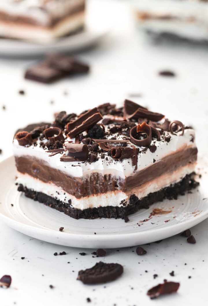 A slice of chocolate lasagna with a bite taken out of it on a small, white plate.