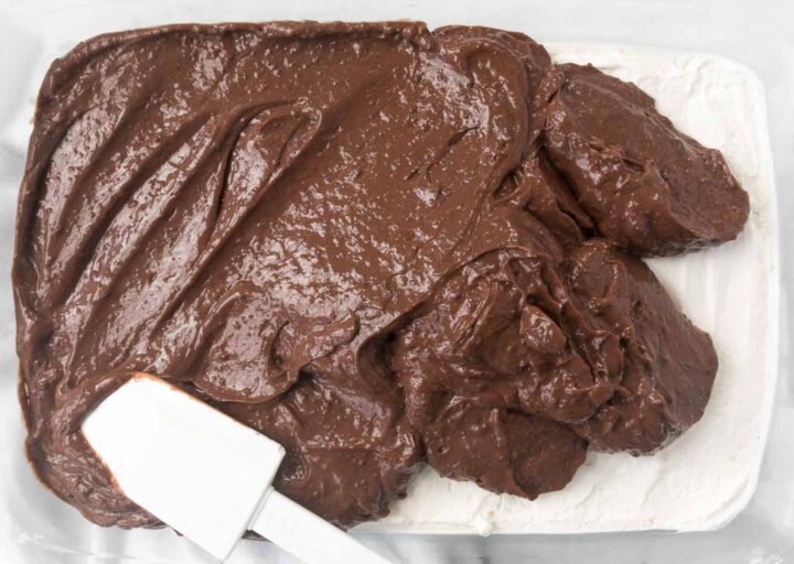Chocolate pudding spread into a baking dish with a white spatula.