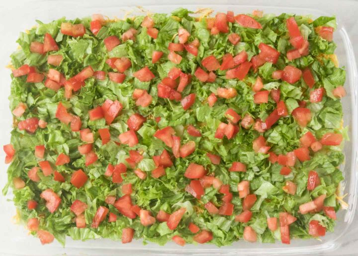 shredded lettuce and diced tomato spread across a 9x13 glass baking dish.