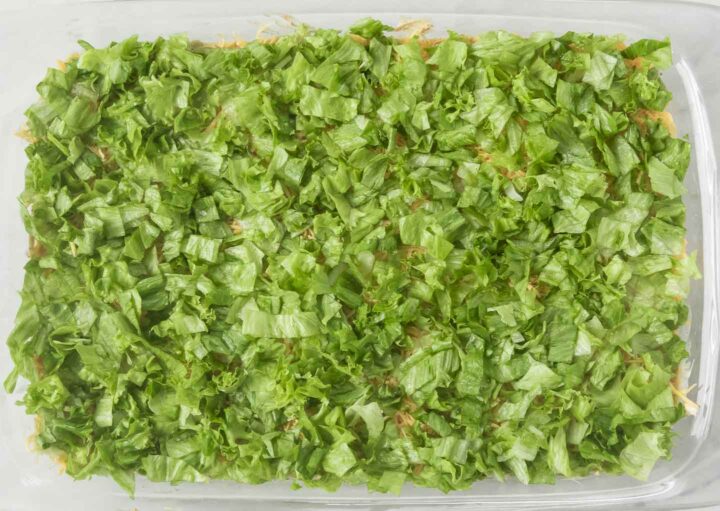 shredded green iceberg lettuce spread out into a 9x13 baking dish.