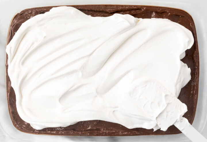 Cool Whip being spread into a clear 9x13 baking dish.