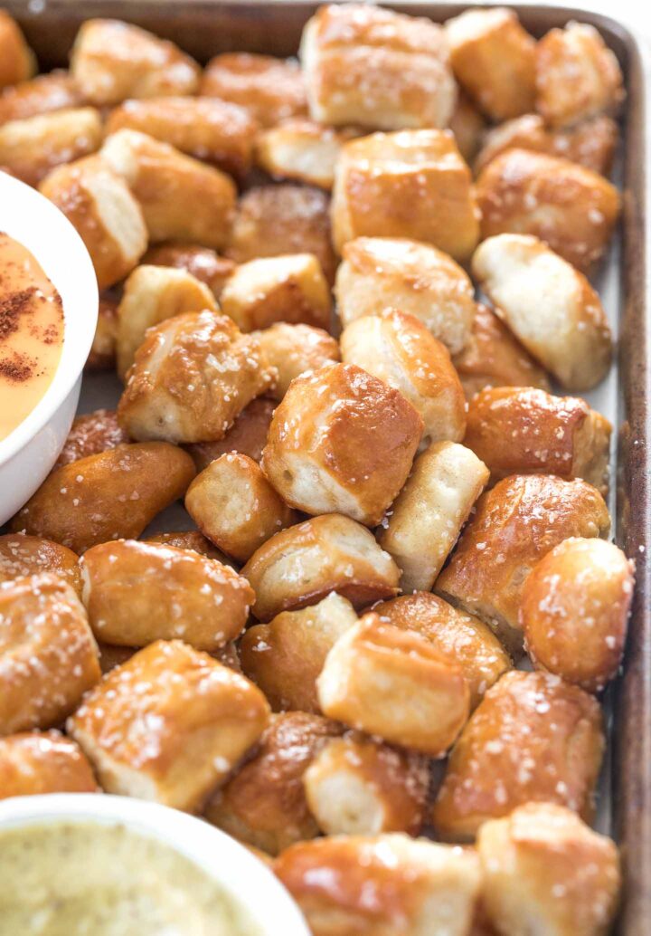 soft pretzel bites on a tray with coarse salt sprinkled on them and a small white bowl with nacho cheese sauce