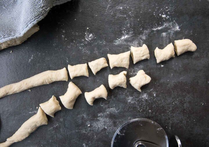 pretzel dough rolled out and being cut into two inch strips