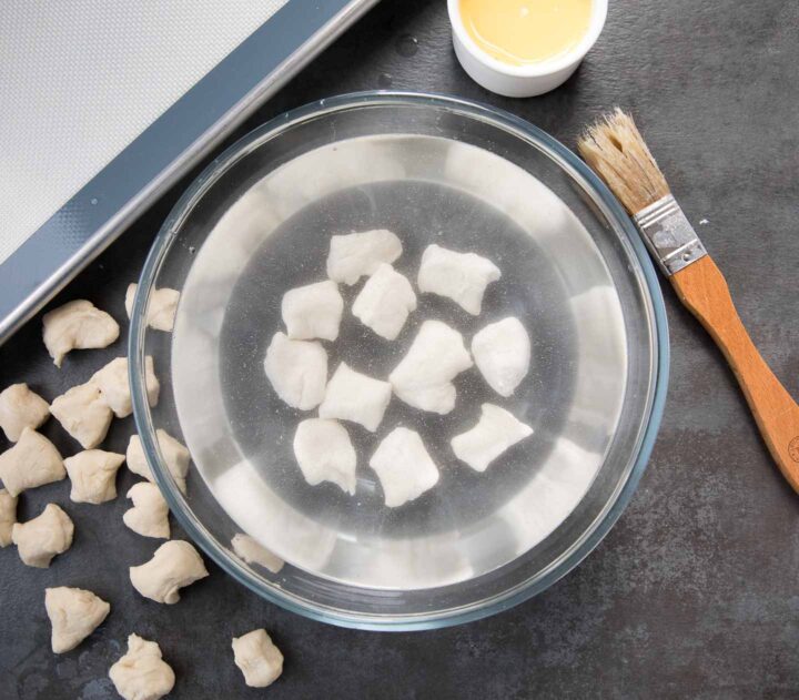 pretzel dough bites sitting in a baking soda bath