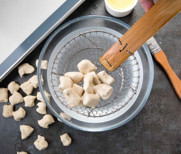 pretzel dough bites being pulled out of a baking soda bath