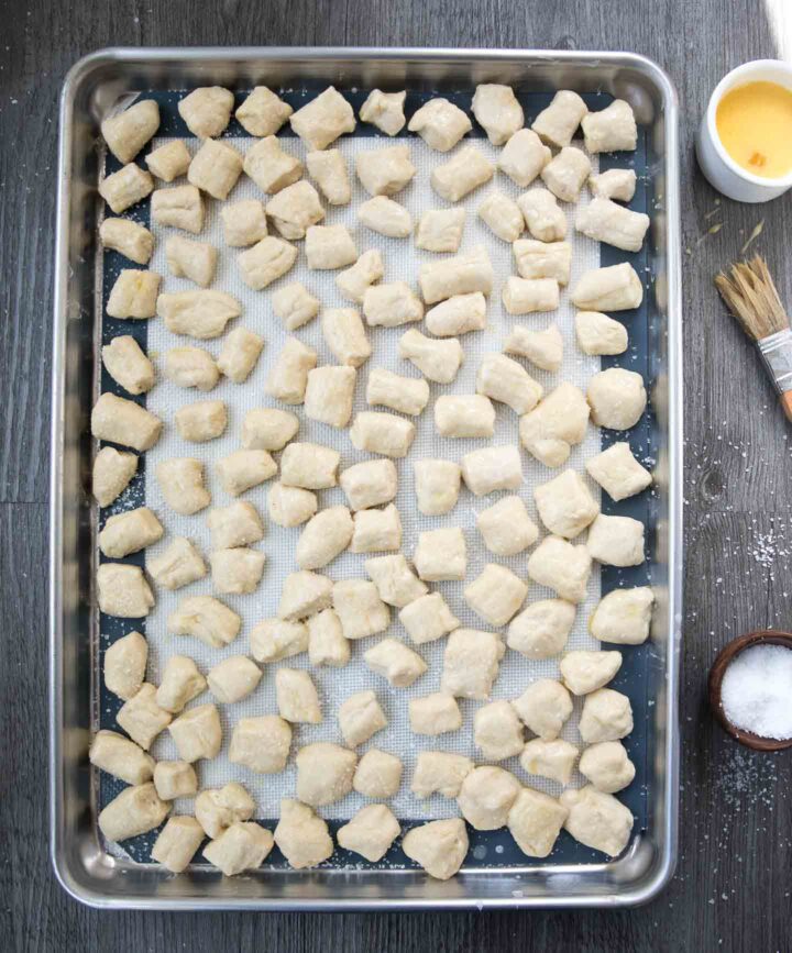 Soft pretzel bites dough on a baking sheet brushed with an egg wash before baking