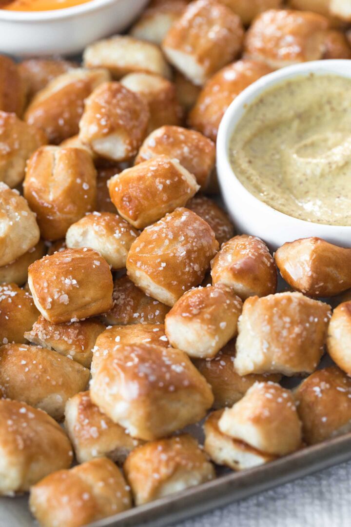 Soft pretzel bites brushed with melted butter and topped with coarse salt on a plate with spicy mustard