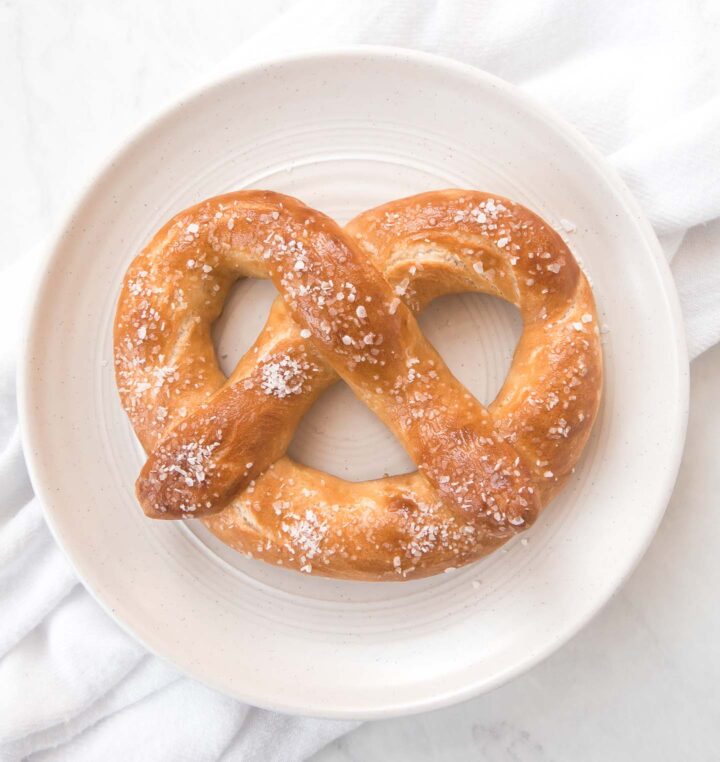 Homemade soft pretzels with coarse salt on a white plate.