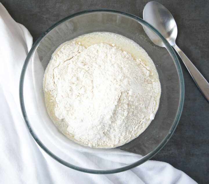 Flour, sugar, yeast and milk in a bowl.